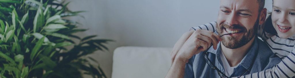 image shows child with arms around father's neck.