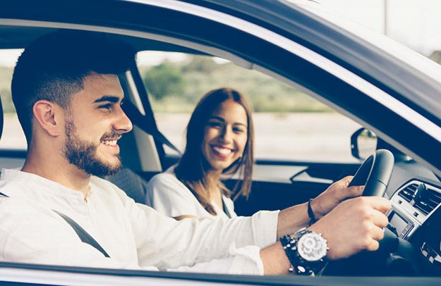 Image shows two people in a car smiling.